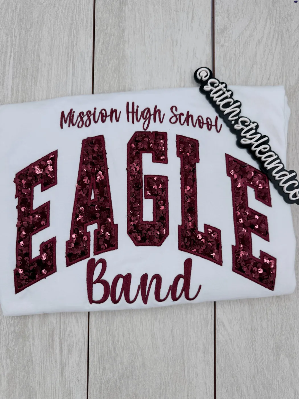 White shirt reading Mission High School EAGLE Band in maroon sequins and script