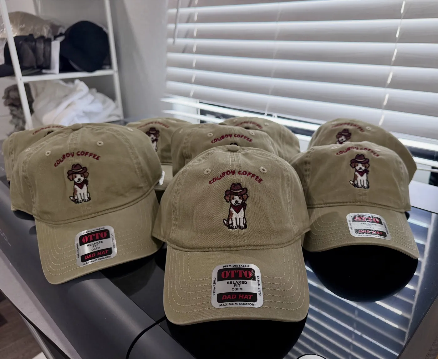 A batch of tan dad caps with a stitched custom logo
