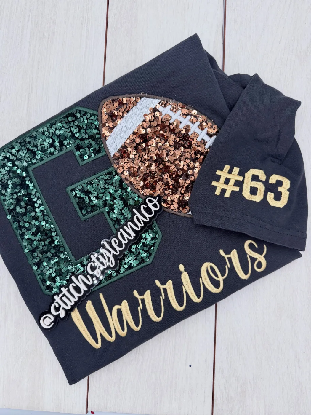 Navy shirt with green sequin G and bronze sequin football, Warriors in script, #63 on the sleeve